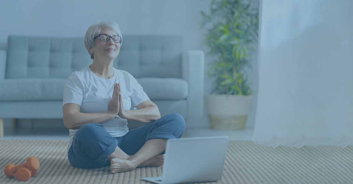 Senior retired woman doing yoga indoors and watching online class